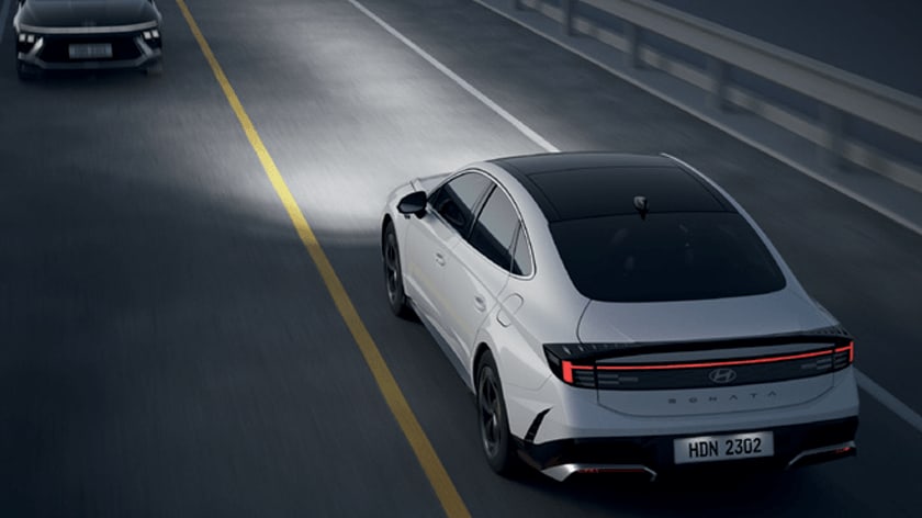 יונדאי לבנה נוסעת על הכביש עם אורות דולקים בחושך