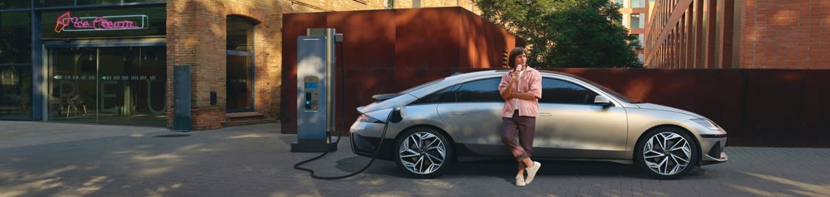 אדם נשען על הרכב בזמן טעינת הרכב