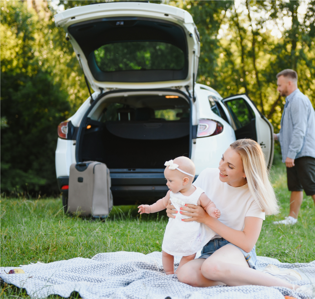 אמא ותינוקת יושבות על דשא ליד רכב חדש בליסינג גמיש