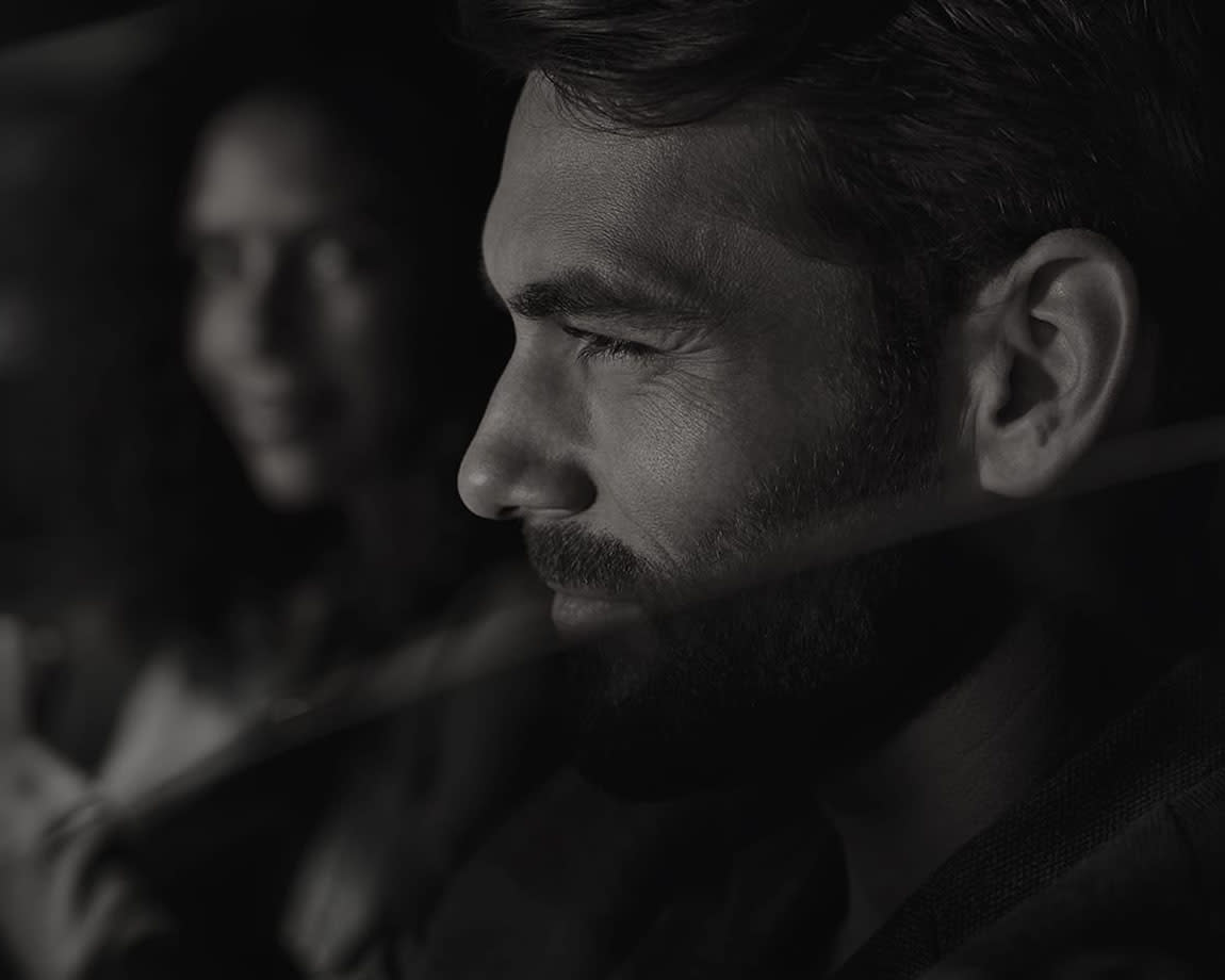 תקריב על פנים של גבר ואישה מחייכת ברקע - תמונה בשחור לבן