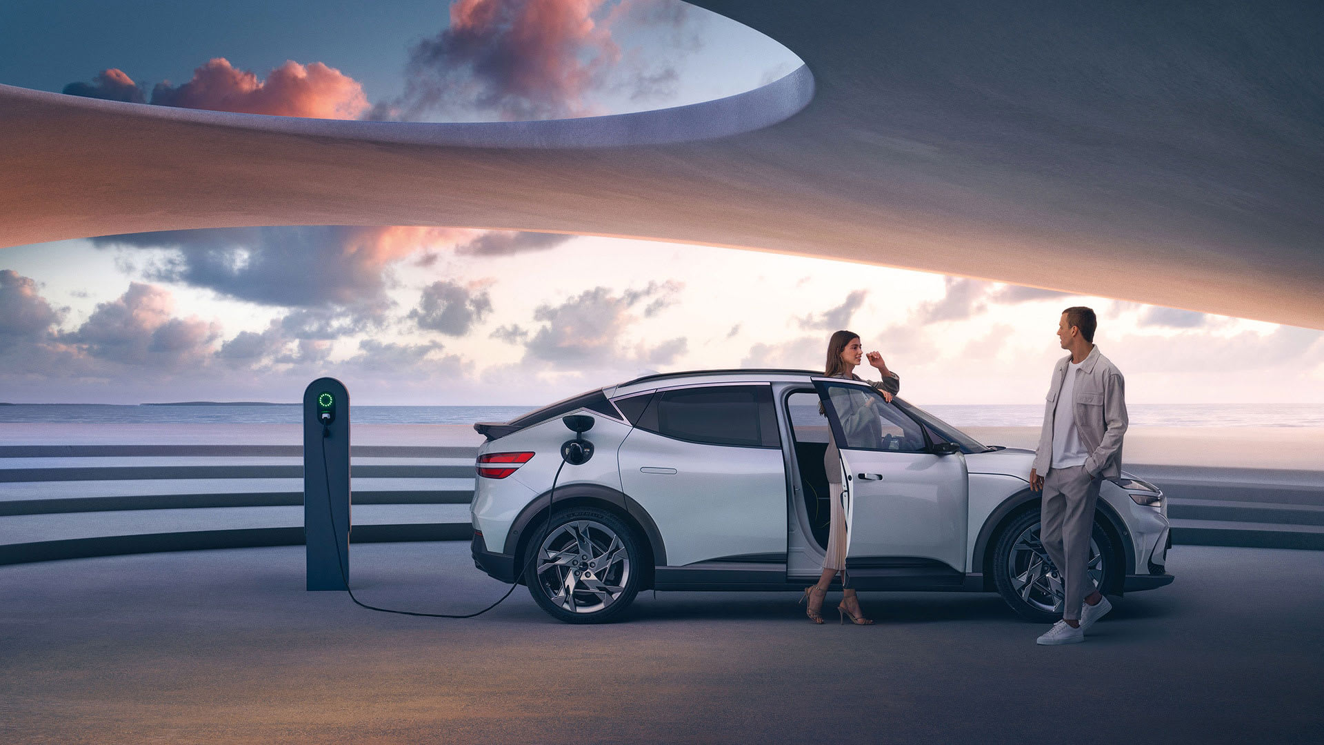 רכב חשמלי יוקרתי מדגם ג'נסיס GV60 EV בצבע לבן בעמדת טעינה חשמלית