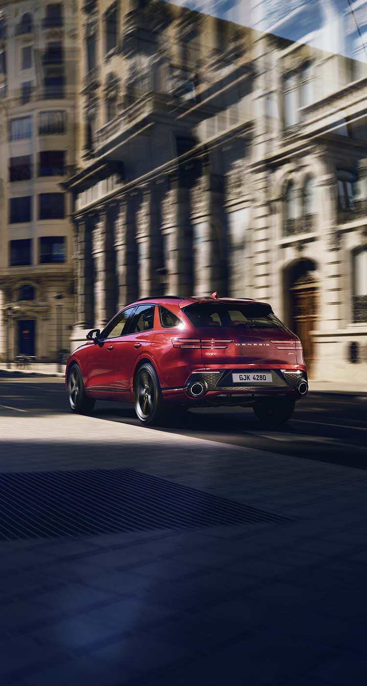 ג'נסיס GV70 בצבע אדום נוסעת בעיר בספרד - טרייד אין רכבי יוקרה