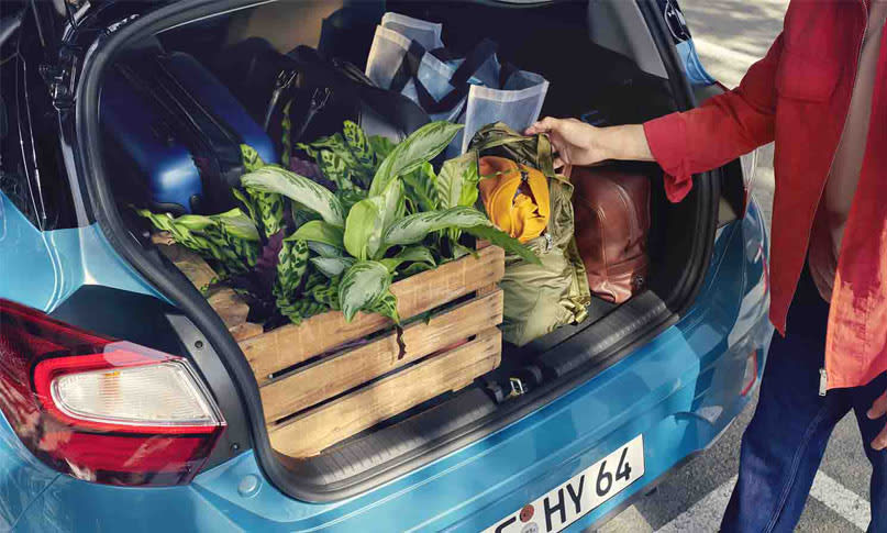 תא מטען של יונדאי i10 מלא בשקיות מזון, ארגז עץ עם צמחים, תיקים ומזוודה