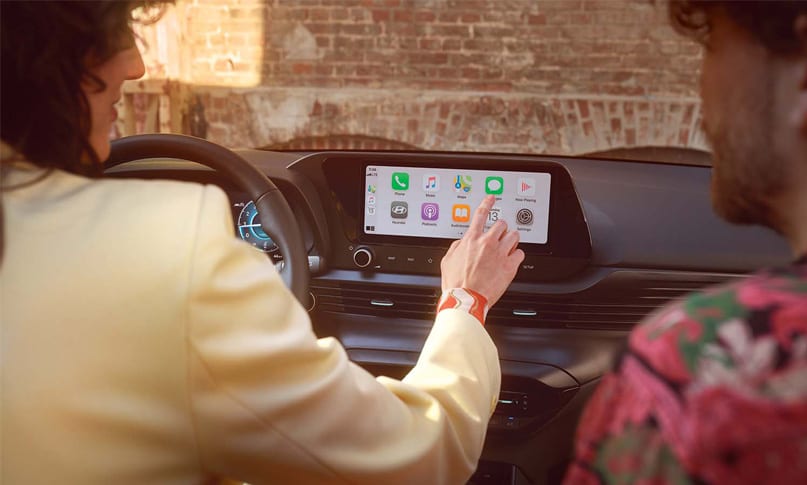 נהגת נוגעת במסך מולטימדיה של יונדאי באיון וגבר יושב לצידה