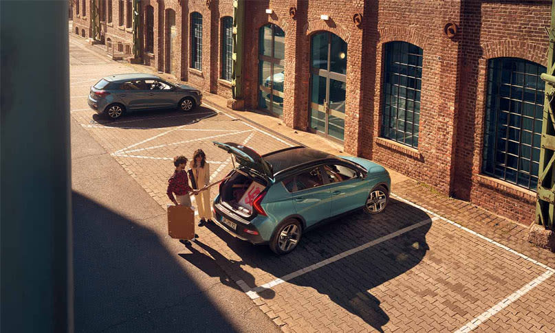 יונדאי באיון BAYON בצבע ירוקבחנייה עם דלת תא מטען פתוחה וגבר ואישה עומדים מולה