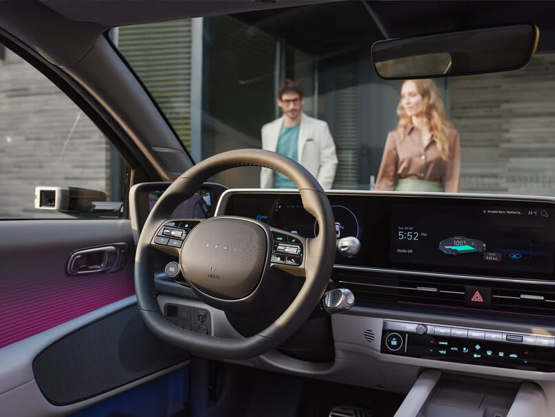 צילום של ההגה והצג מול ההגה צילום מאחורה וצד. דרך זכוכית החלון רואים גבר ואישה