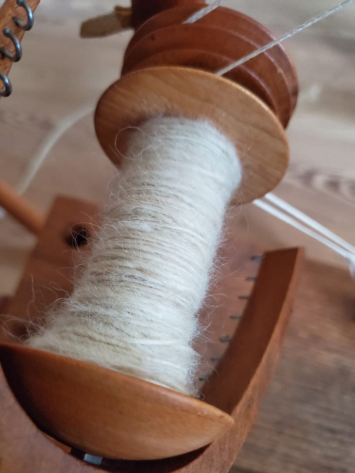 Spinning some hand-dyed wool into yarn using a wooden spinning