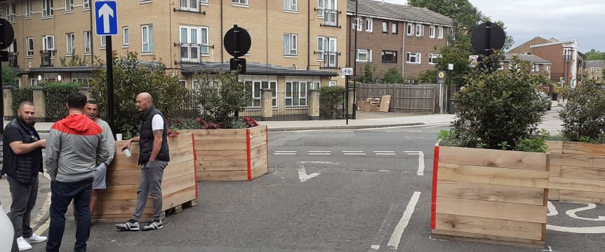 Four people meeting by large planters on Gore Road 