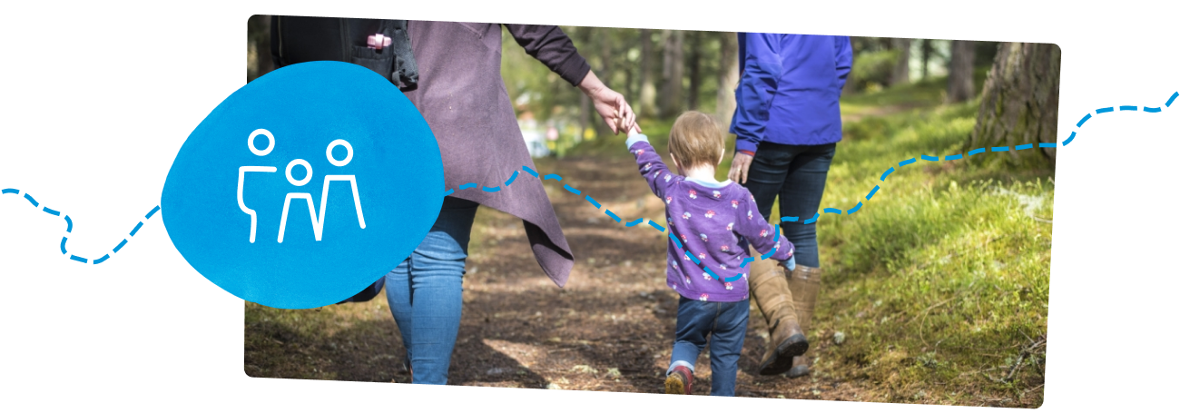 Young child holding mothers hand on woodland walk