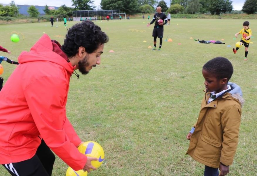 An image of a man coaching a young boy in football.