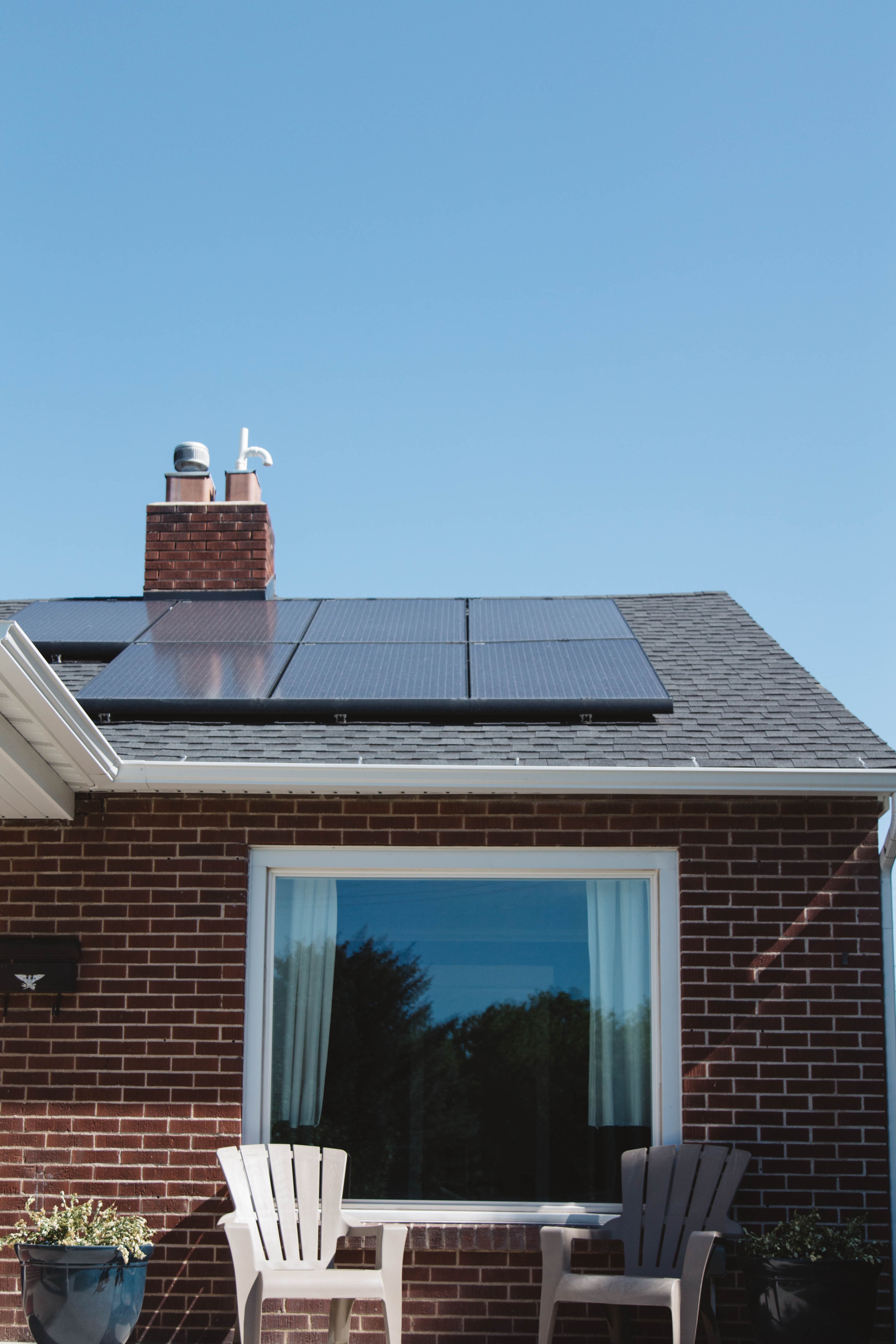 A house roof has 6 square black solar panels on it facing the sun