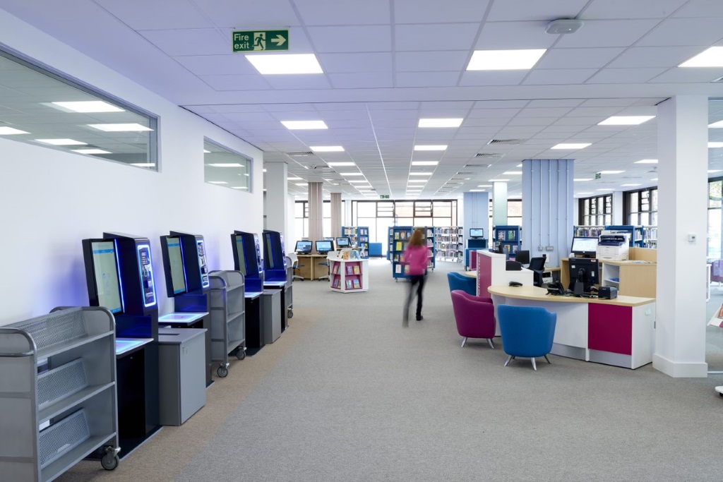 Image of a potential entrance spare in a library with a reception desk and self check in machines