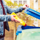 A person putting a plastic bleach bottle into a recycling bin