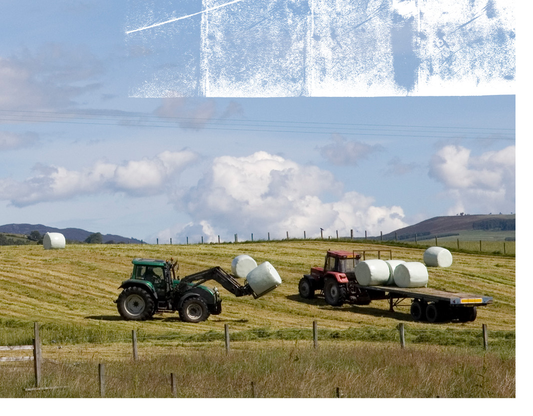 Tractors in field bailing hay