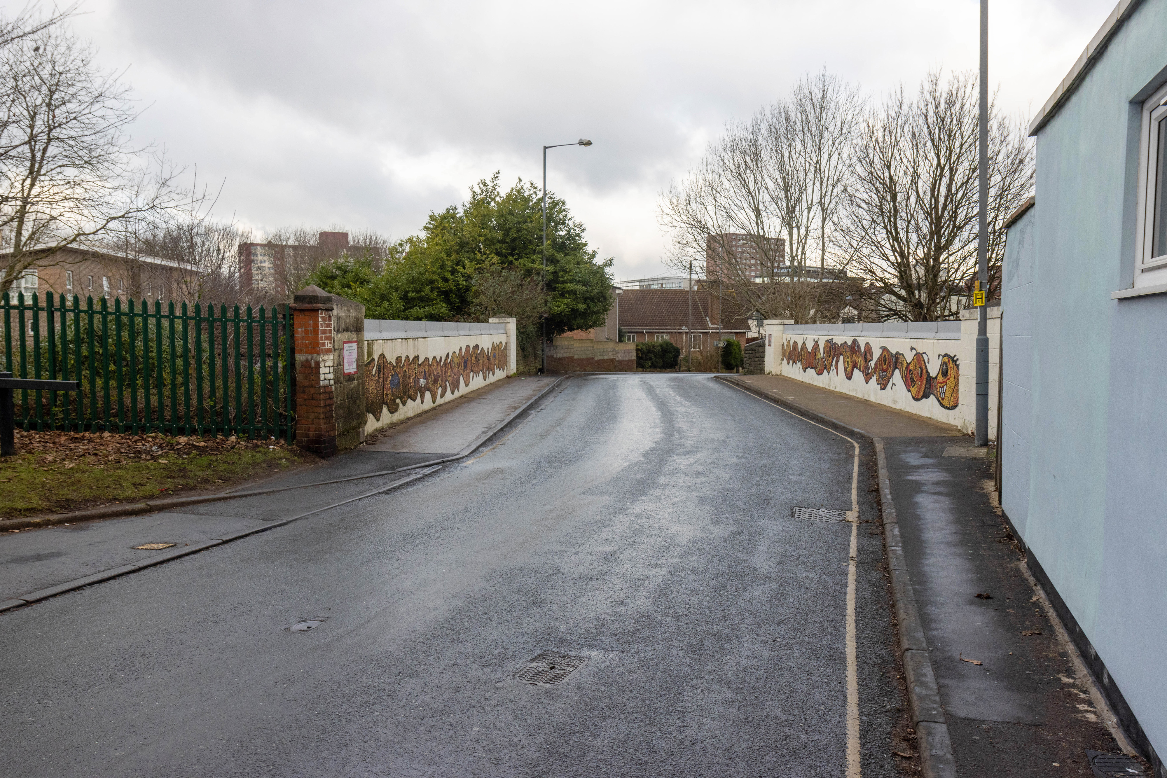 Empty road across the railway bridge. Single yellow lines on either side of the street. 