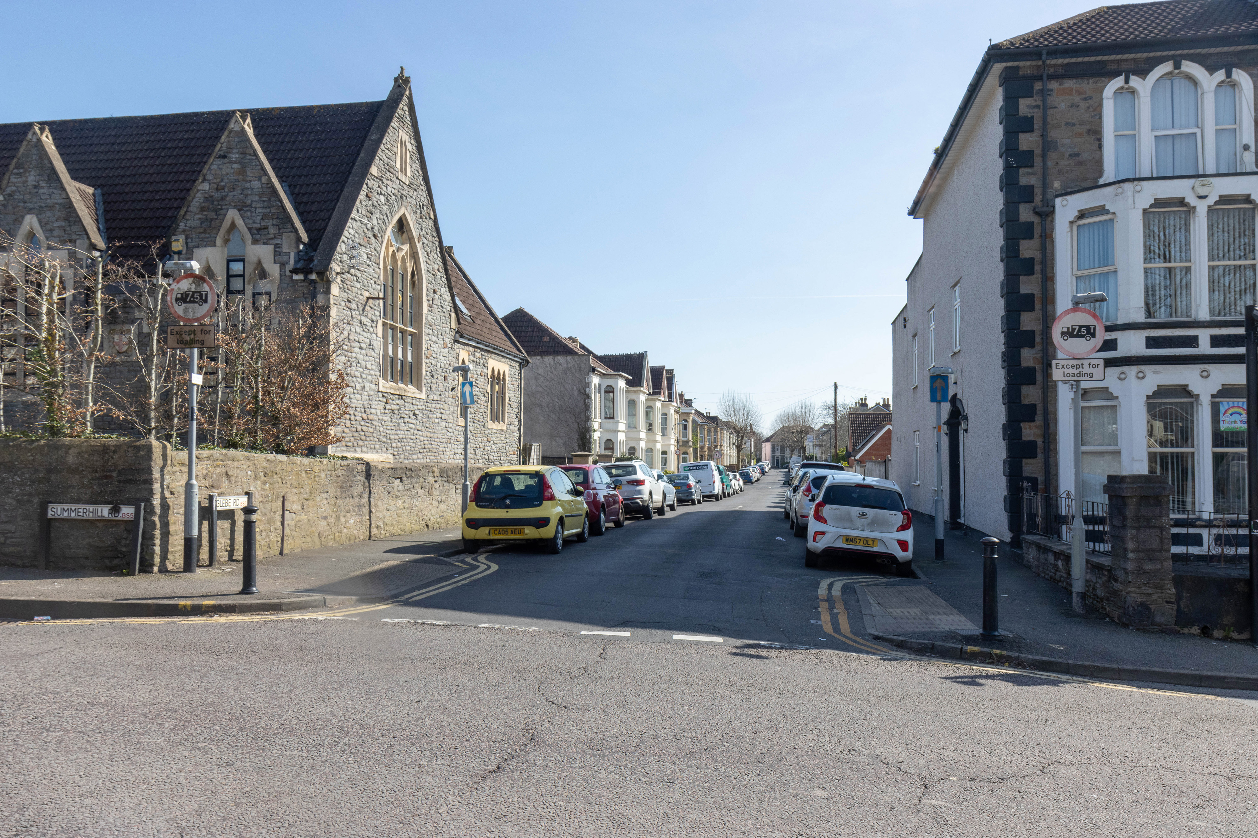 Cars parked on both sides of the street with informal pedestrian crossing over Glebe Road. 