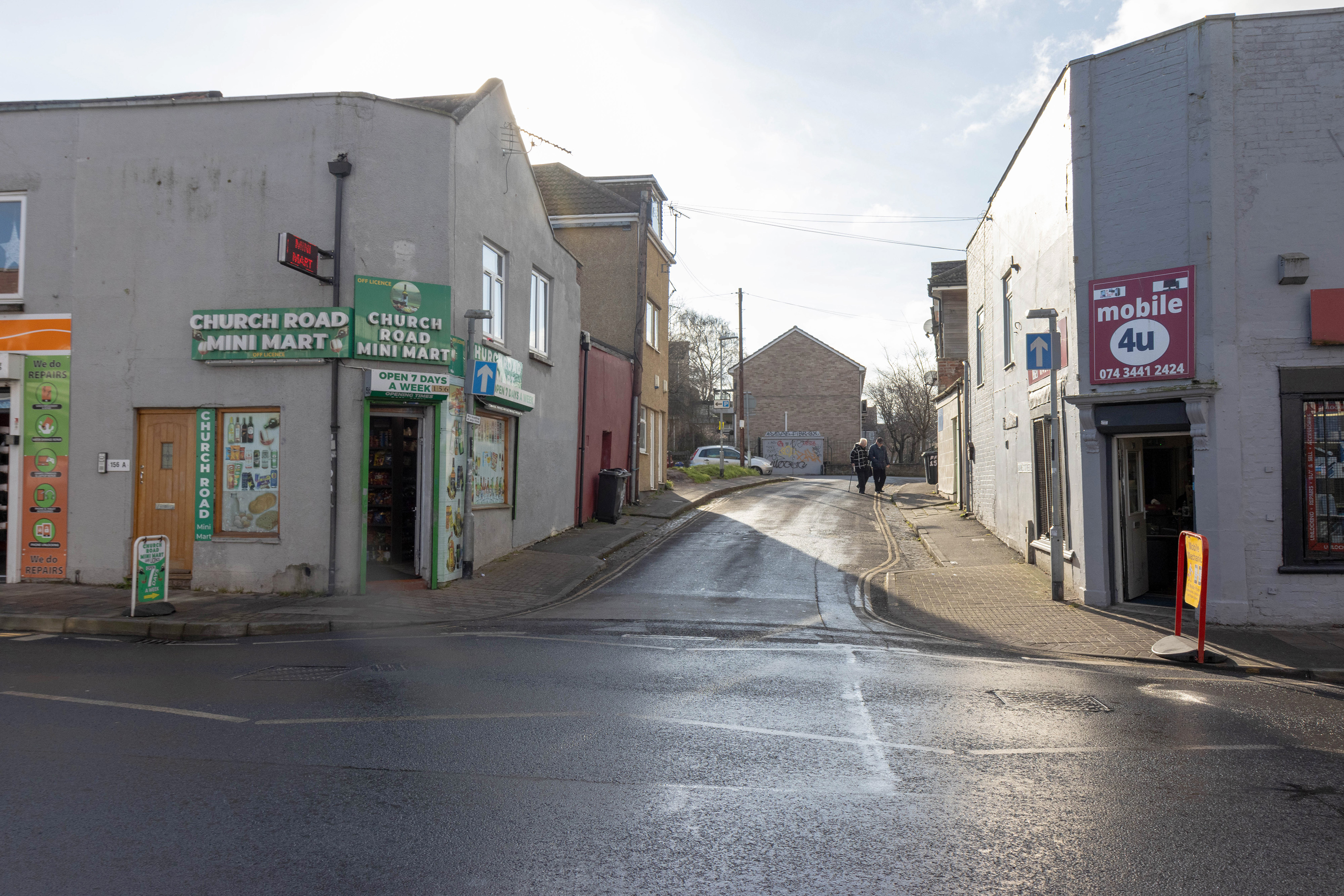 Empty street with double yellow lines and bins on the pavement. No entry road signs on columns.