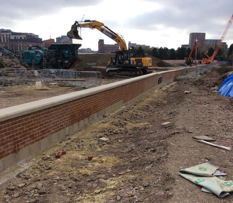 A newly constructed flood wall with a JCB in the background