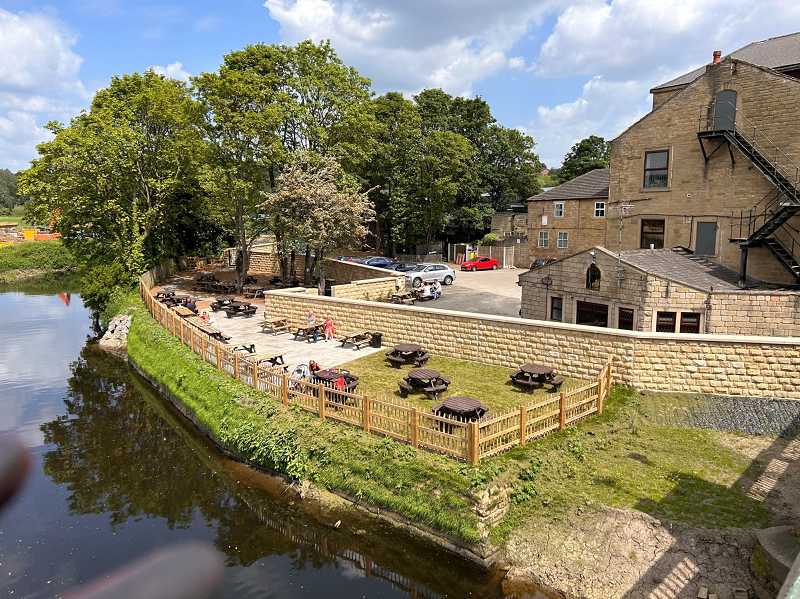 flood walls surrounding the Kirkstall Bridge Inn, with a reinstated garden and seating around the outside