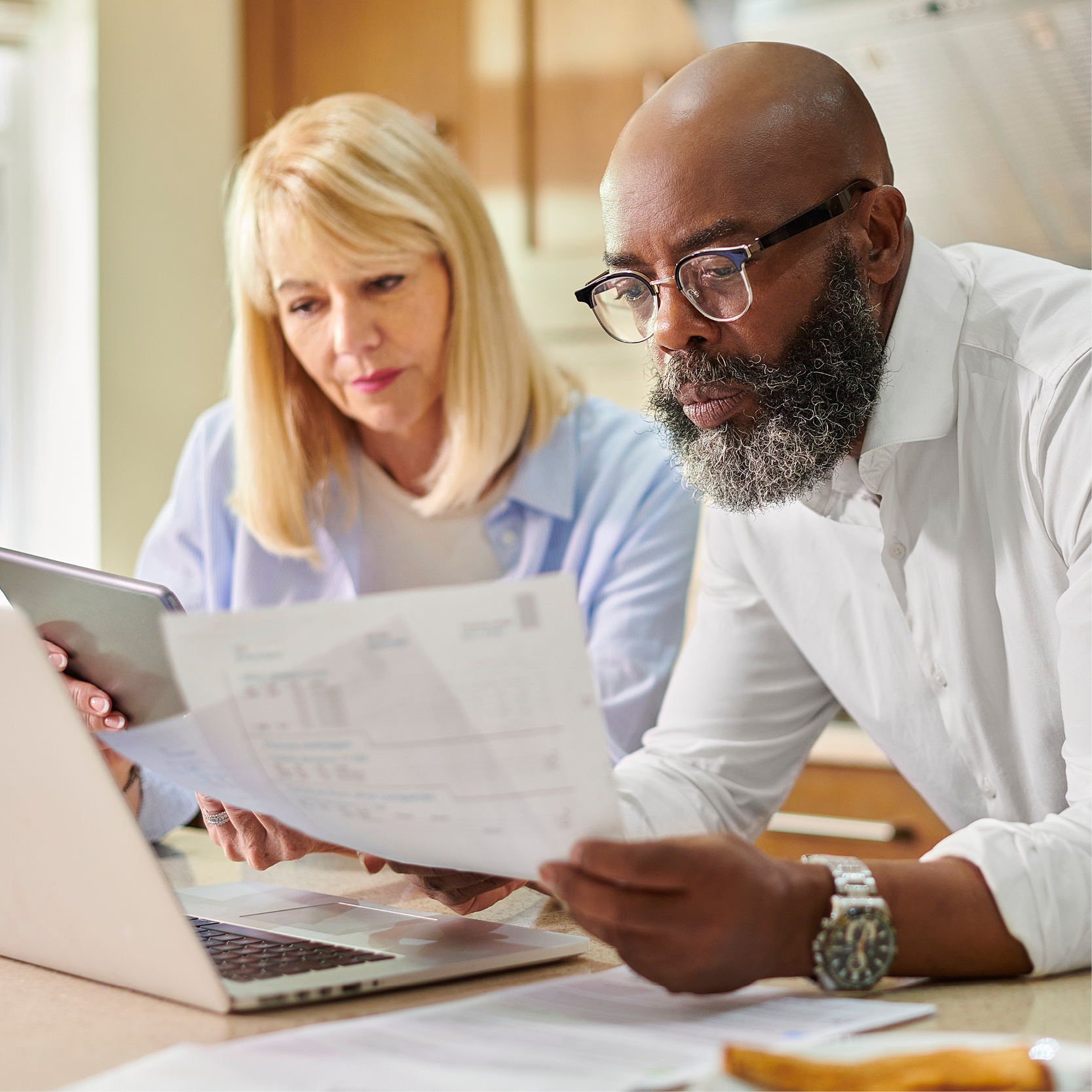 A man and woman looking at their finance paperwork with a laptop in front of them planning their finances.