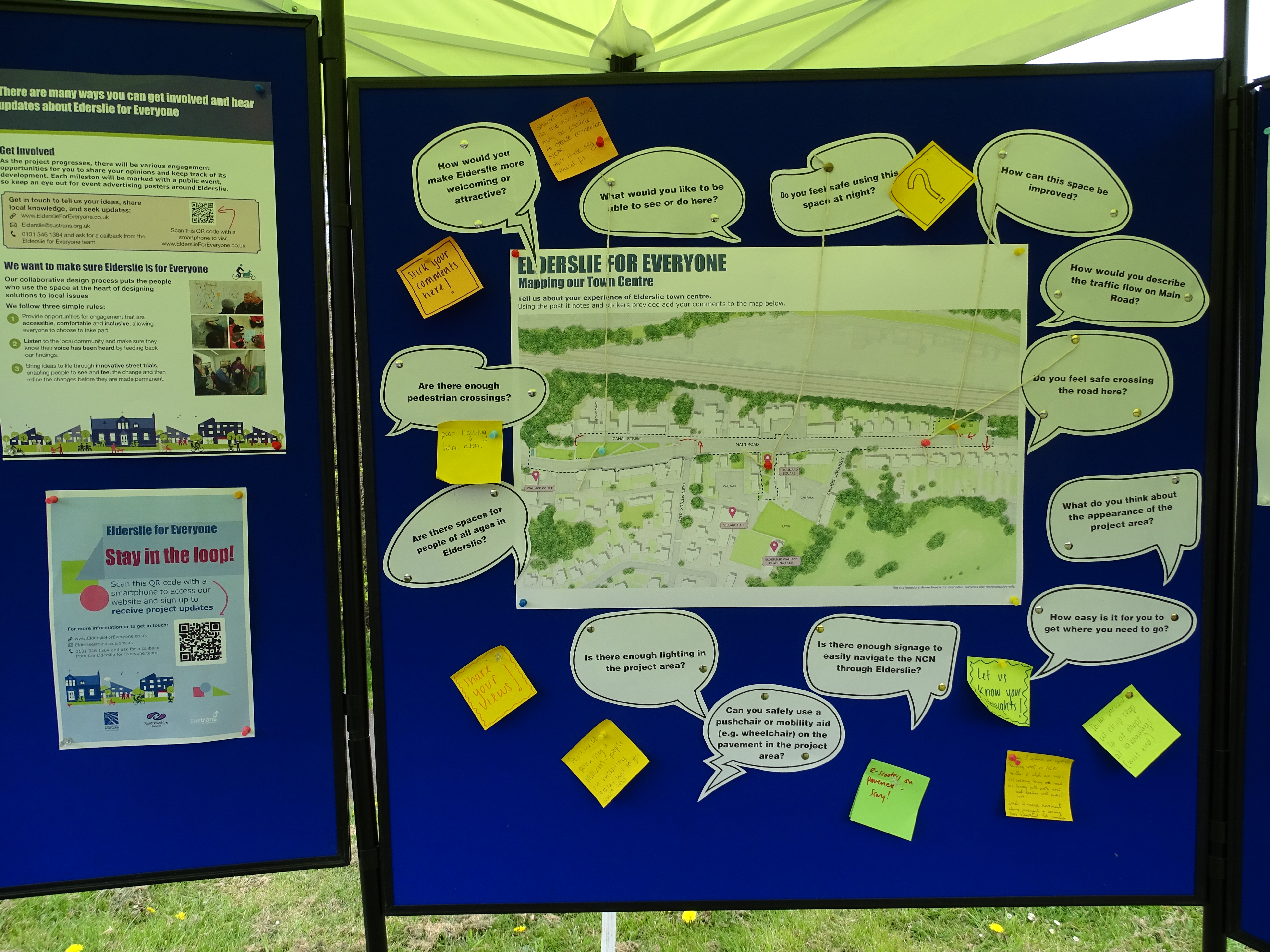 An image of a blue pin board with a map of Elderslie Main Road with questions in speech bubble circles around it and sqaure colourful post it notes with writing on it