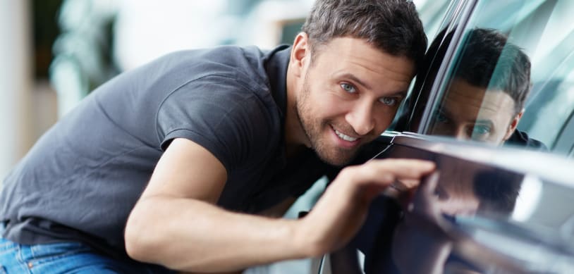 Joven mirando su auto asegurado