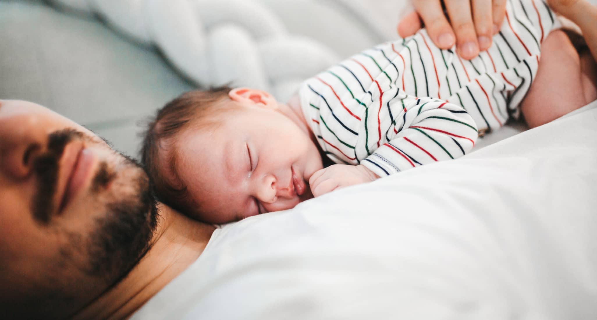 A newborn baby sleeping on their father’s chest.