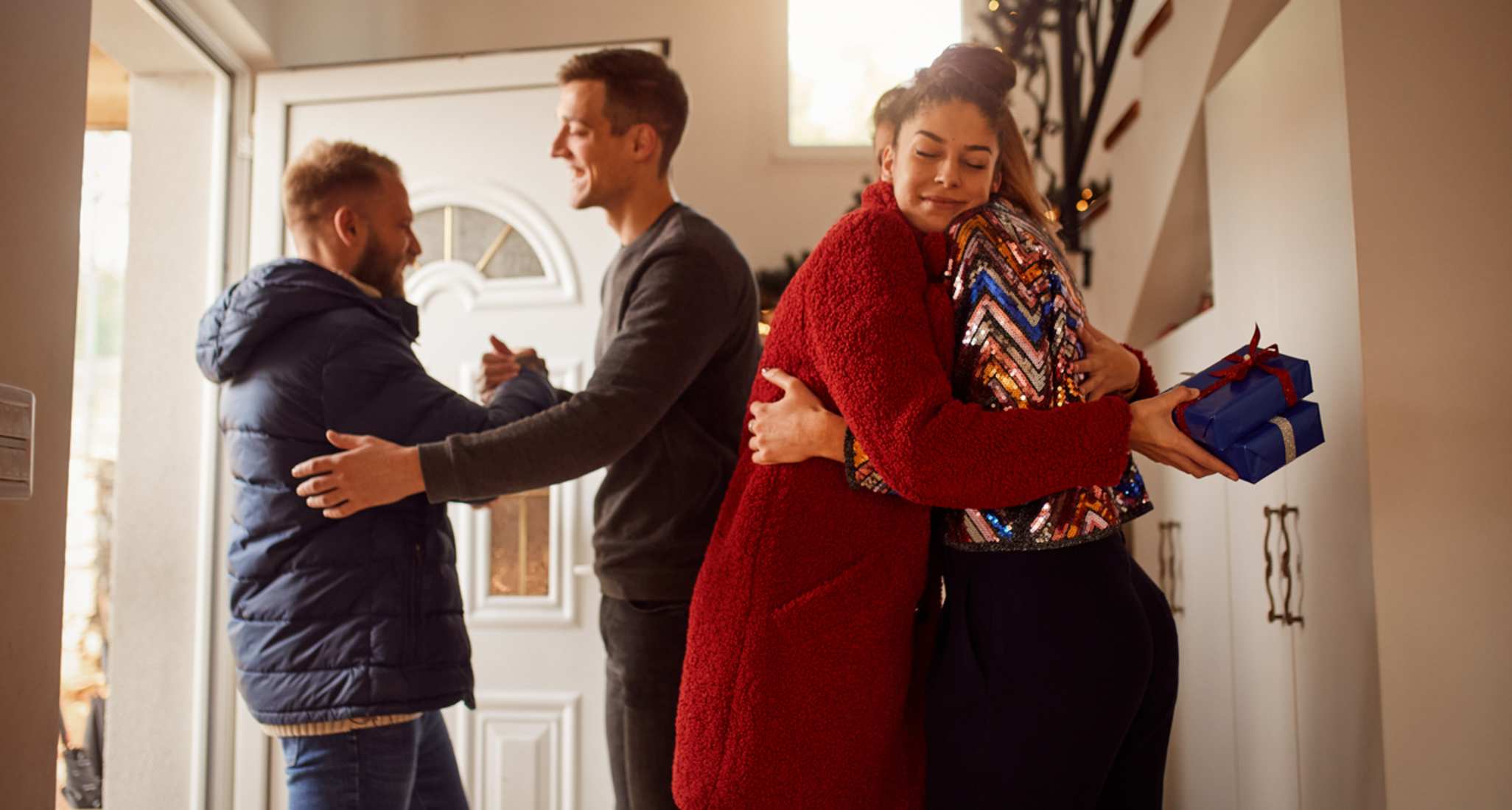 Four people greet each other outside a door.