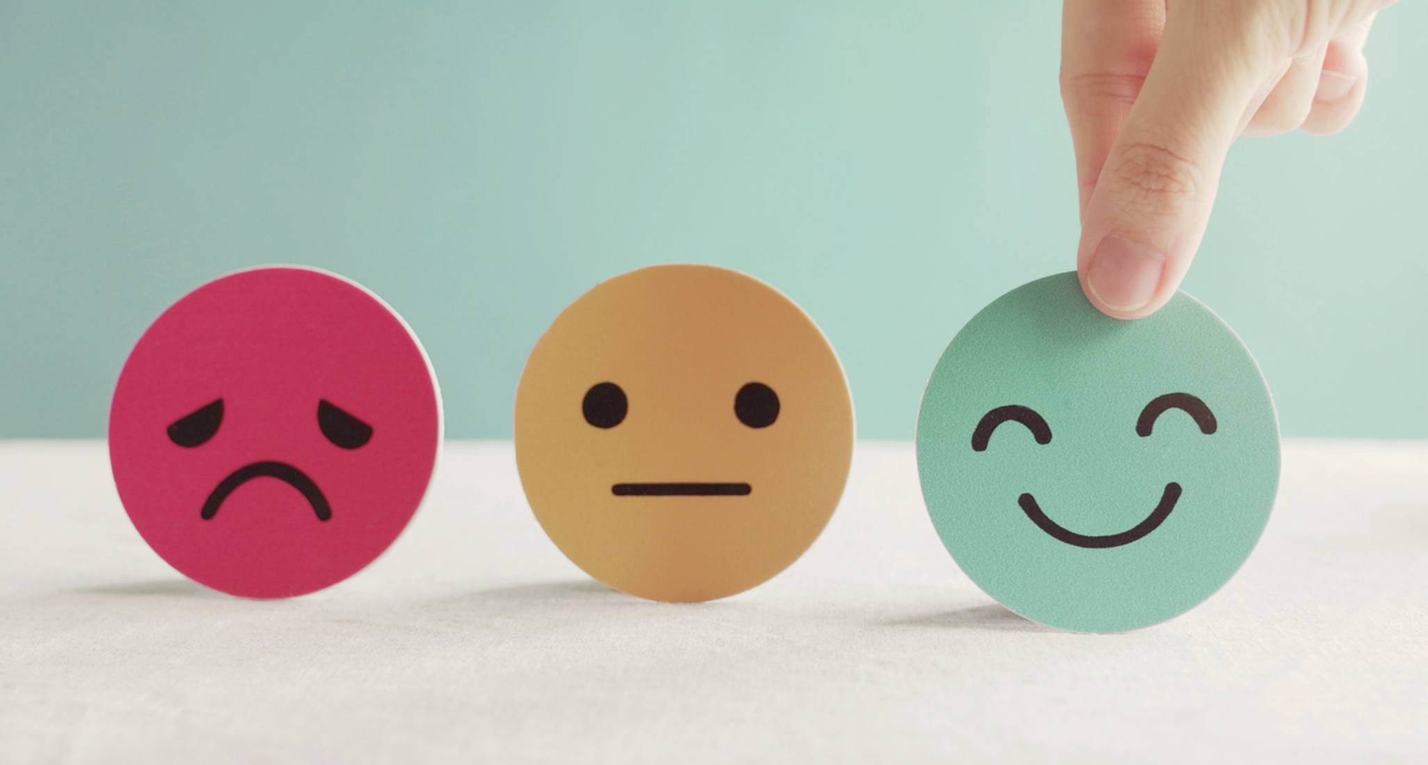 Three emojis in red, green and yellow are placed on a table.