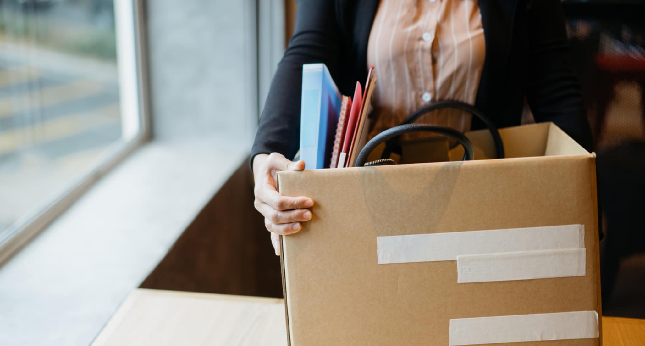 Una donna ha messo le sue cose dal posto di lavoro in una scatola marrone