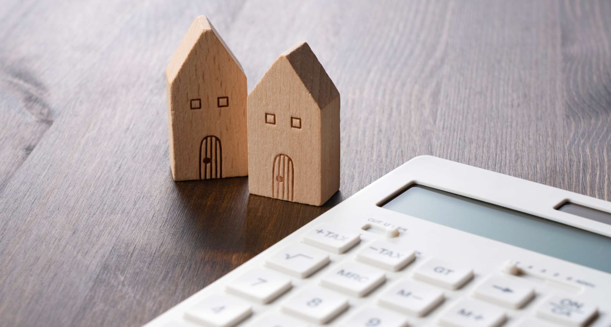 Deux maisons de jouets en bois se trouvent à côté d’une calculatrice.