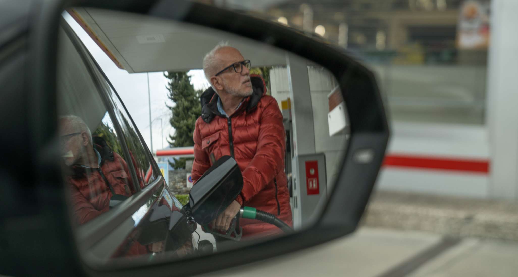 Un signore anziano fa il pieno alla sua auto.