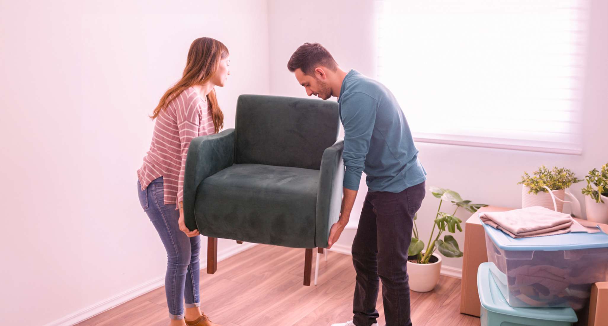 Una donna e un uomo decorano il soggiorno e dispongono i mobili.