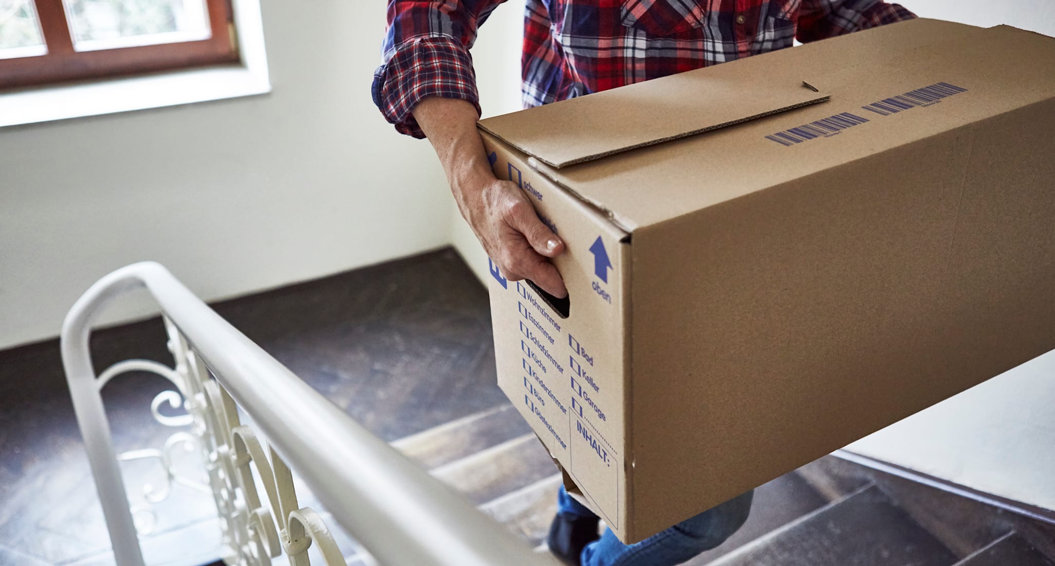 A person carrying a moving box up the stairs.