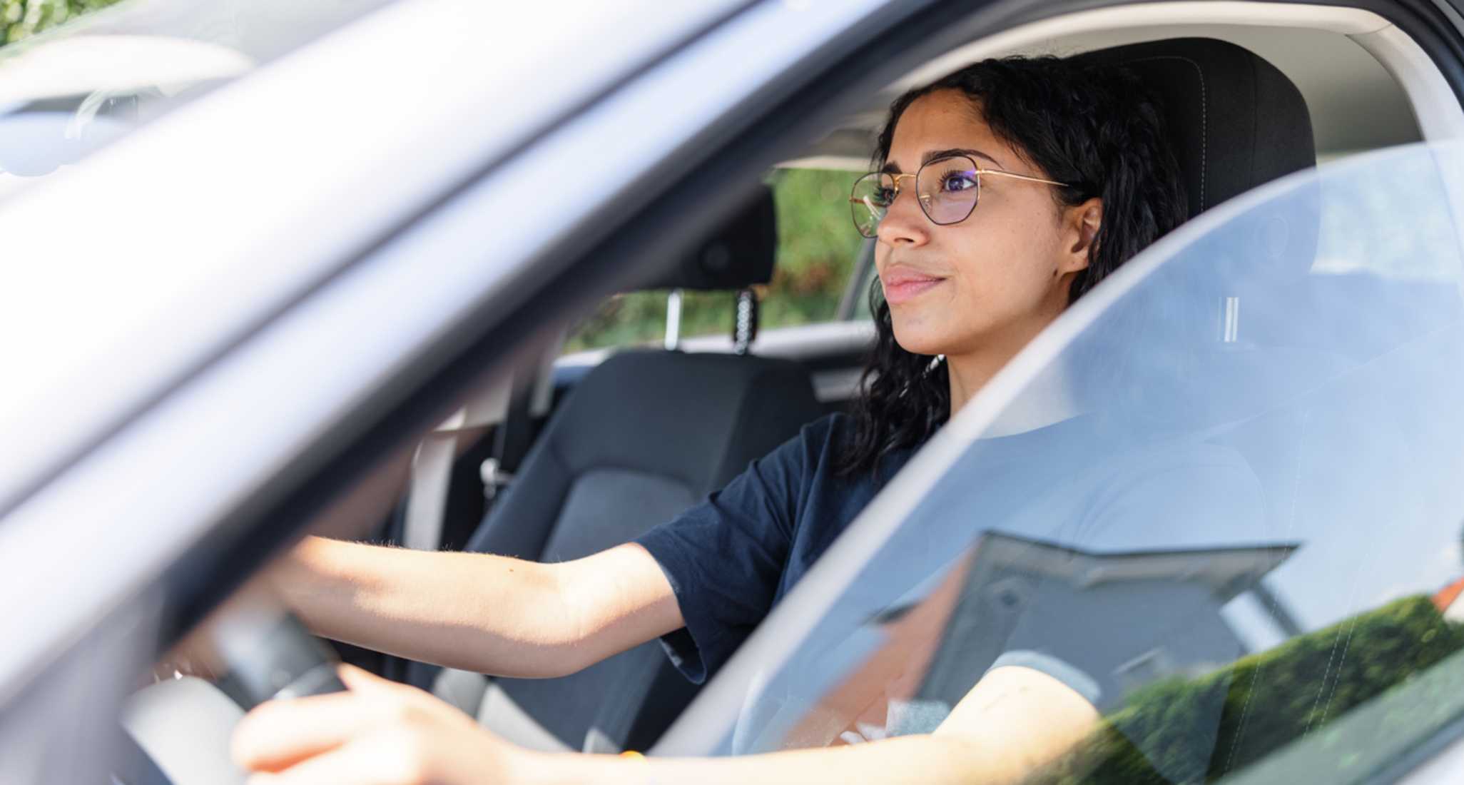 Junge Frau sitzt am Lenkrad eines Autos.