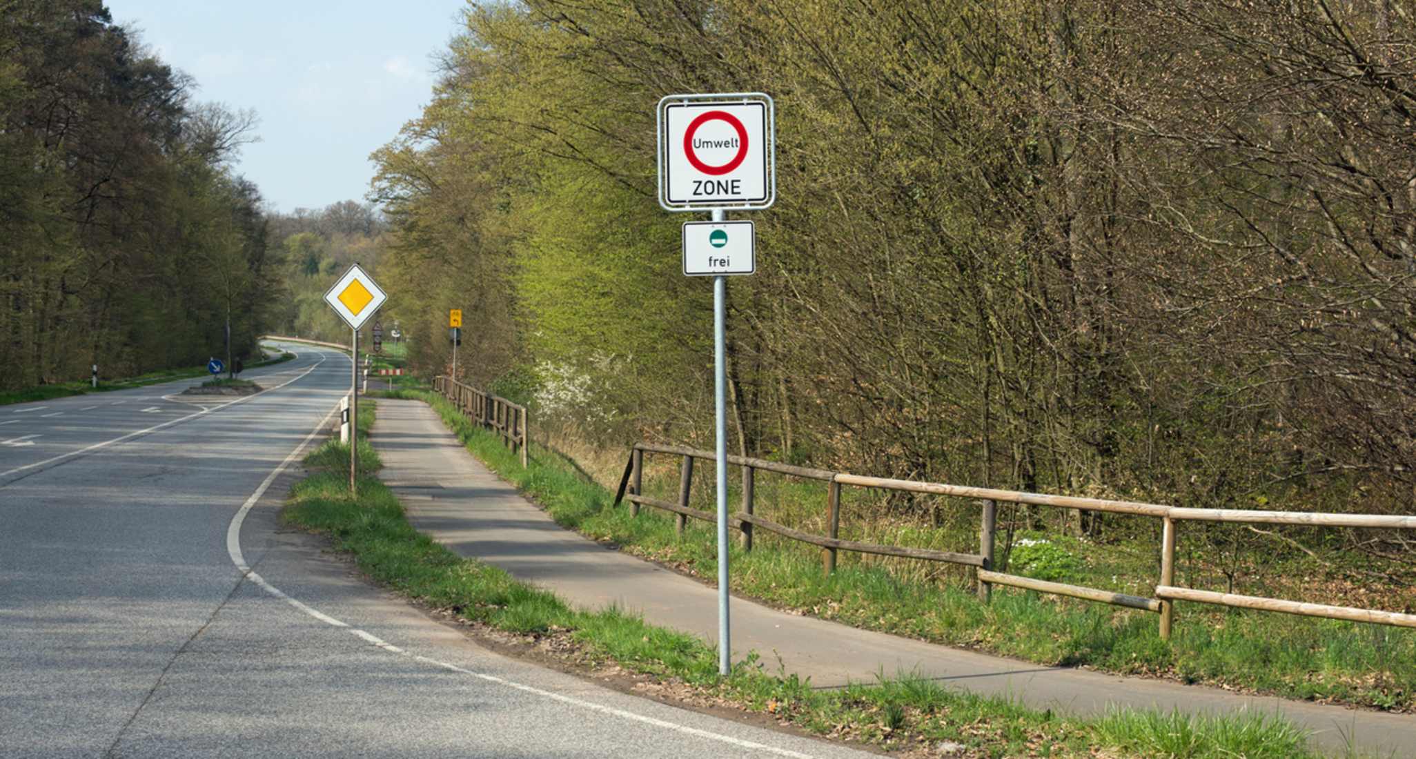 Country road on the edge of the forest with traffic sign "environmental zone" and the addition "free".