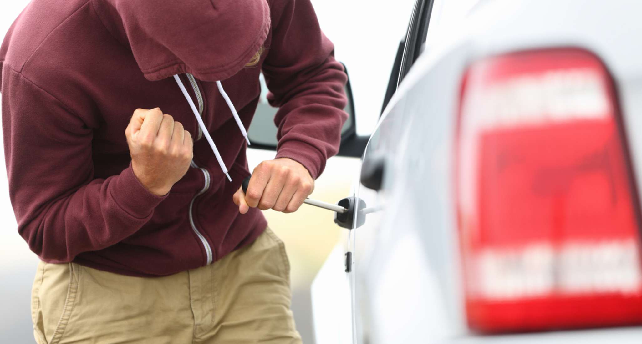 A man trying to steal a car.