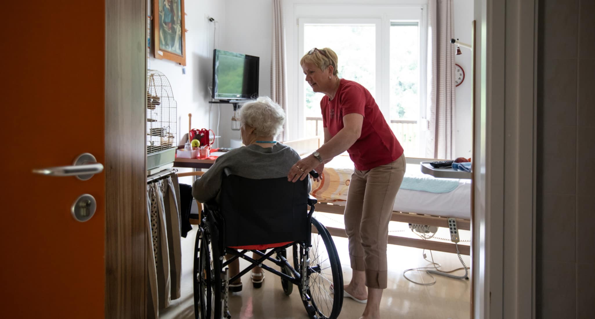 Eine Pflegerin hilft einer älteren Dame im Rollstuhl.