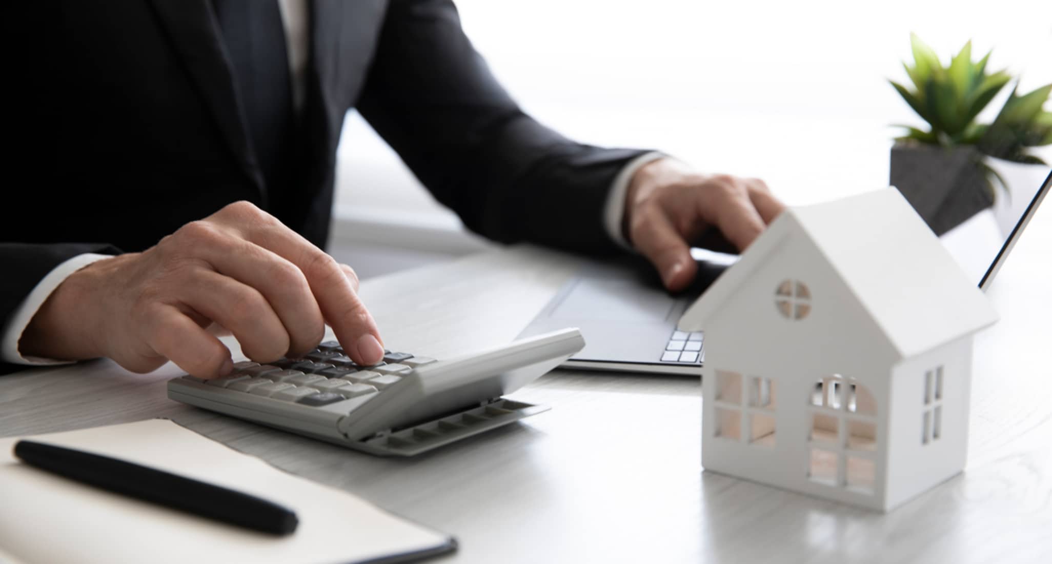 Un uomo calcola con una calcolatrice i costi per l’acquisto di una casa.