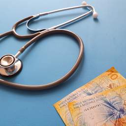 Un stéthoscope et des francs suisses sont sur une table.