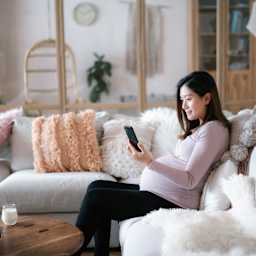 A pregnant woman explores possible health insurance options on her mobile phone.