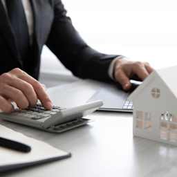 Mann berechnet mit Taschenrechner die Kosten, die beim Hauskauf anfallen.