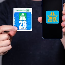 Person hält die neue Autobahnvignette 2024 und E-Vignette 2024 in den Händen.