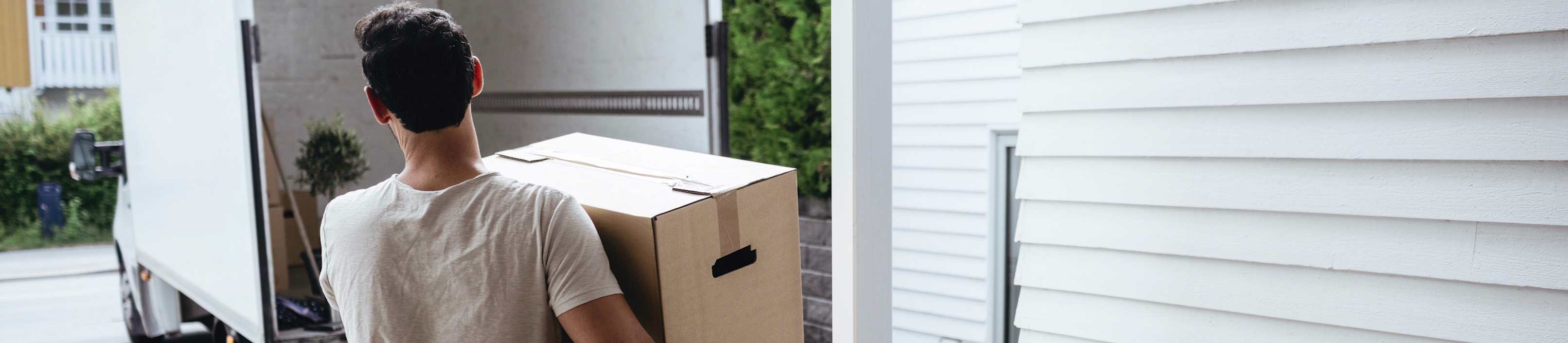 Mann räumt Kartons in den Transporter.