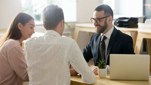 Una giovane coppia parla con un consulente ipotecario di diversi tassi di interesse.