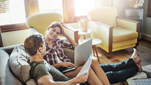 Ein Paar sitzt auf dem Sofa und schaut auf einen Laptop.