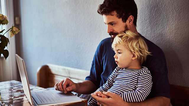 Father and son sit at a laptop.