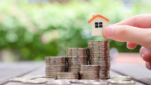 A small house that is placed on a stack of coins.
