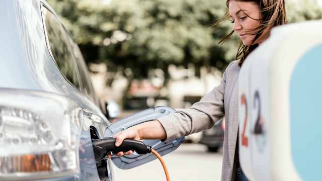 Une jeune femme recharge sa voiture électrique en ville.