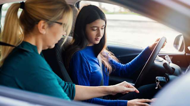 Fahrlehrerin erklärt Fahrschülerin den Aufbau des Autos.